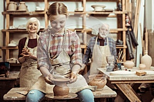 Grandmother and grandfather with granddaughter making pottery