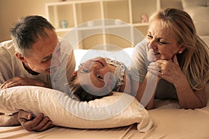 Grandmother and grandfather lie together with their granddaughter.