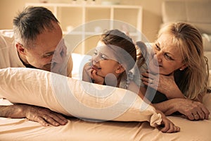 Grandmother and grandfather lie together with their granddaughter.