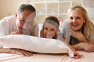 Grandmother and grandfather lie together with their granddaughter.