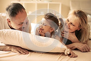 Grandmother and grandfather lying together with their granddaughter.