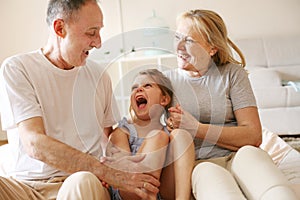 Grandmother and grandfather sitting together with their granddaughter.