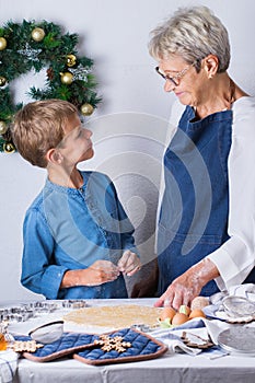 Grandmother with grandson cooking, kneading dough, baking in the kitchen