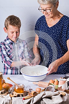 Grandmother with grandson cooking, kneading dough, baking in the kitchen