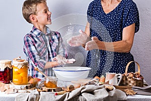 Grandmother with grandson cooking, kneading dough, baking in the kitchen