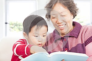 Grandmother and grandson are reading story book together