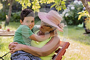 Grandmother and grandson are sitting in the summer garden