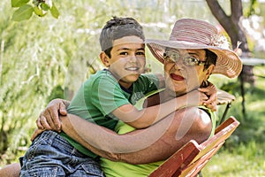 Grandmother and grandson are sitting in the summer garden