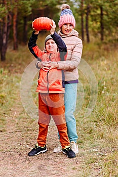 Grandmother and grandson take pictures with a pumpkin. harvest