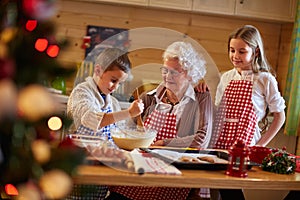 Grandmother helping grandchildren preparing Christmas cookies