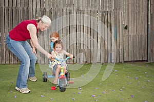 Grandmother helping kids ride trike