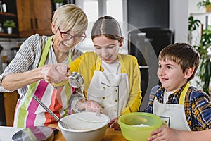 Grandmother and her grandchildren making cakes together in the home kitchen