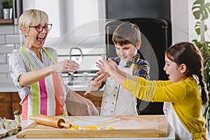 Grandmother and her grandchildren making cakes together in the home kitchen