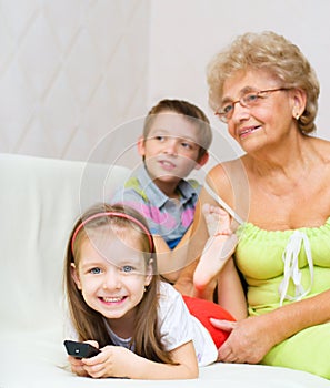 Grandmother with her grandchildren are watching TV