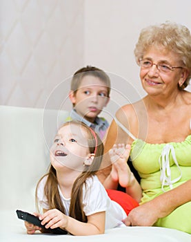 Grandmother with her grandchildren are watching TV