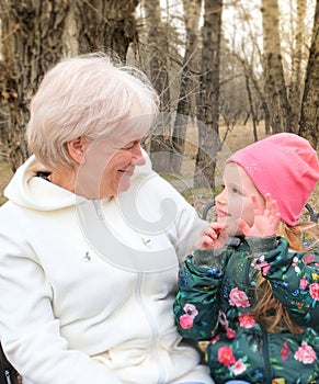 Grandmother with her granddaughter hugging and talking  sitting on a bench in the park