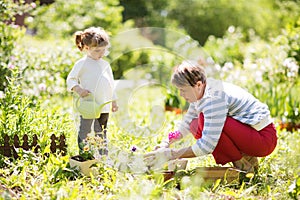 Grandmother with her granddaughter working in the garden.