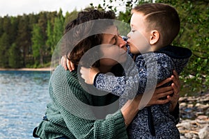 Grandmother and her grandson sitting and hugging hear the sea. Happy kissing family.