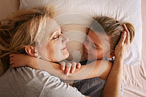 Grandmother and her little granddaughter sleeping together in be