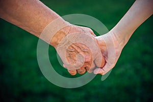 Grandmother holding grandchild hand in nature. National Grandparents Day, family concept. Two generations. The old woman