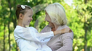 Grandmother holding her granddaughter, child sincerely laughing and smiling