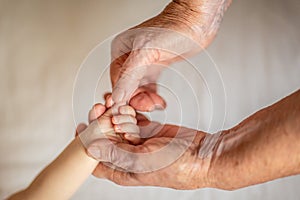 Grandmother holds the hand of her newborn grandson. the concept of protection and care of the new generation