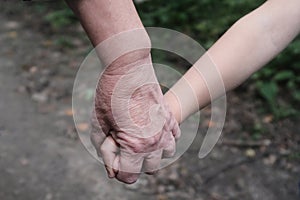 Grandmother holds hands of her grandson close-up. The concept of age difference and love between kindred spirits