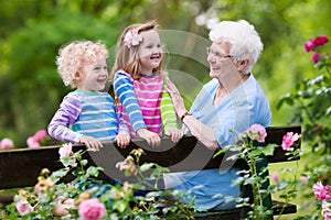 Grandmother and kids sitting in rose garden