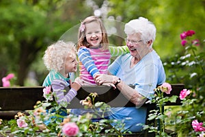 Grandmother and kids sitting in rose garden