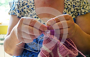 Grandmother knits a sweater for her granddaughter with threads