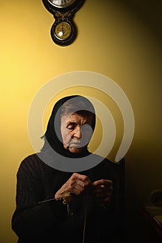 Grandmother knitting. Yarn, knitting needles partially visible. Low key photograph.