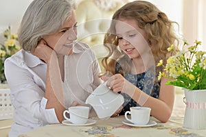 Grandmother with little girl drinking tea