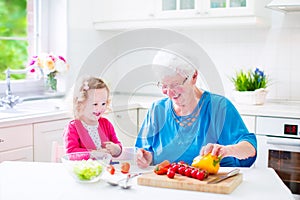 Grandmother and little girl making salad