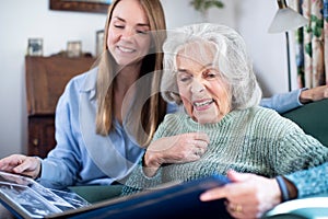 Grandmother Looking At Photo Album With Adult Granddaughter