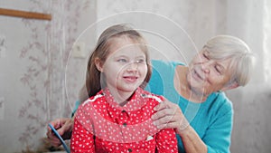 Grandmother makes ponytale on baby`s head. Good time at home.