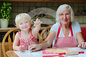 Grandmother making cookies together with granddaughter