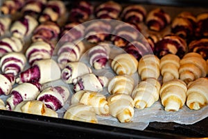 Grandmother making handmade tasty butter rolling cookies with fruit and berry jam on oven tray before baking at kitchen