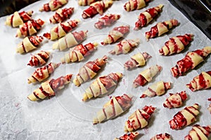 Grandmother making handmade tasty butter rolling cookies with fruit and berry jam on oven tray before baking at kitchen