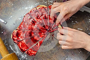 Grandmother making handmade tasty butter rolling cookies with fruit and berry jam on oven tray before baking at kitchen