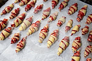 Grandmother making handmade tasty butter rolling cookies with fruit and berry jam on oven tray before baking at kitchen indoor.