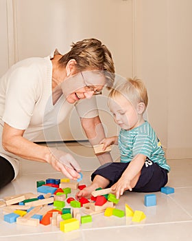 A grandmother or nanny plays with a little boy photo