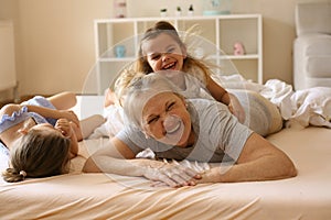 Grandmother playing in bed with her granddaughters.