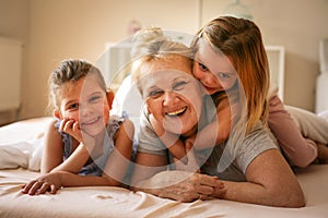 Grandmother playing in bed with her granddaughters.