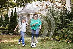 Grandmother Playing Soccer In Garden With Granddaughter