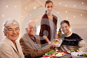 Grandmother, portrait and family at dinner on Christmas, together with food and celebration in home. Happy, event and