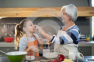 Grandmother putting flour on granddaughters nose