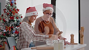 Grandmother putting flour ingredients in strainer explaining to granddaughter