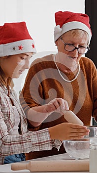 Grandmother putting flour ingredients in strainer explaining to granddaughter