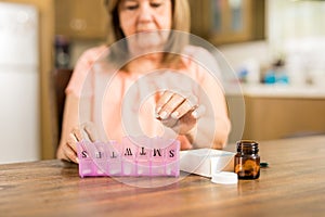 Grandmother putting tablets on a pill box