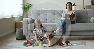 Grandmother read book while her granddaughter playing on the floor